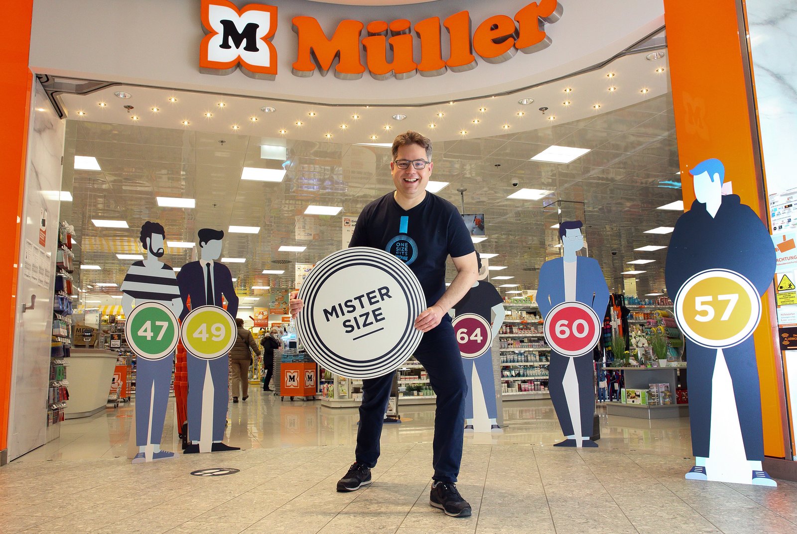 Jan Vinzenz Krause with Mister Size logo in the entrance of Müller