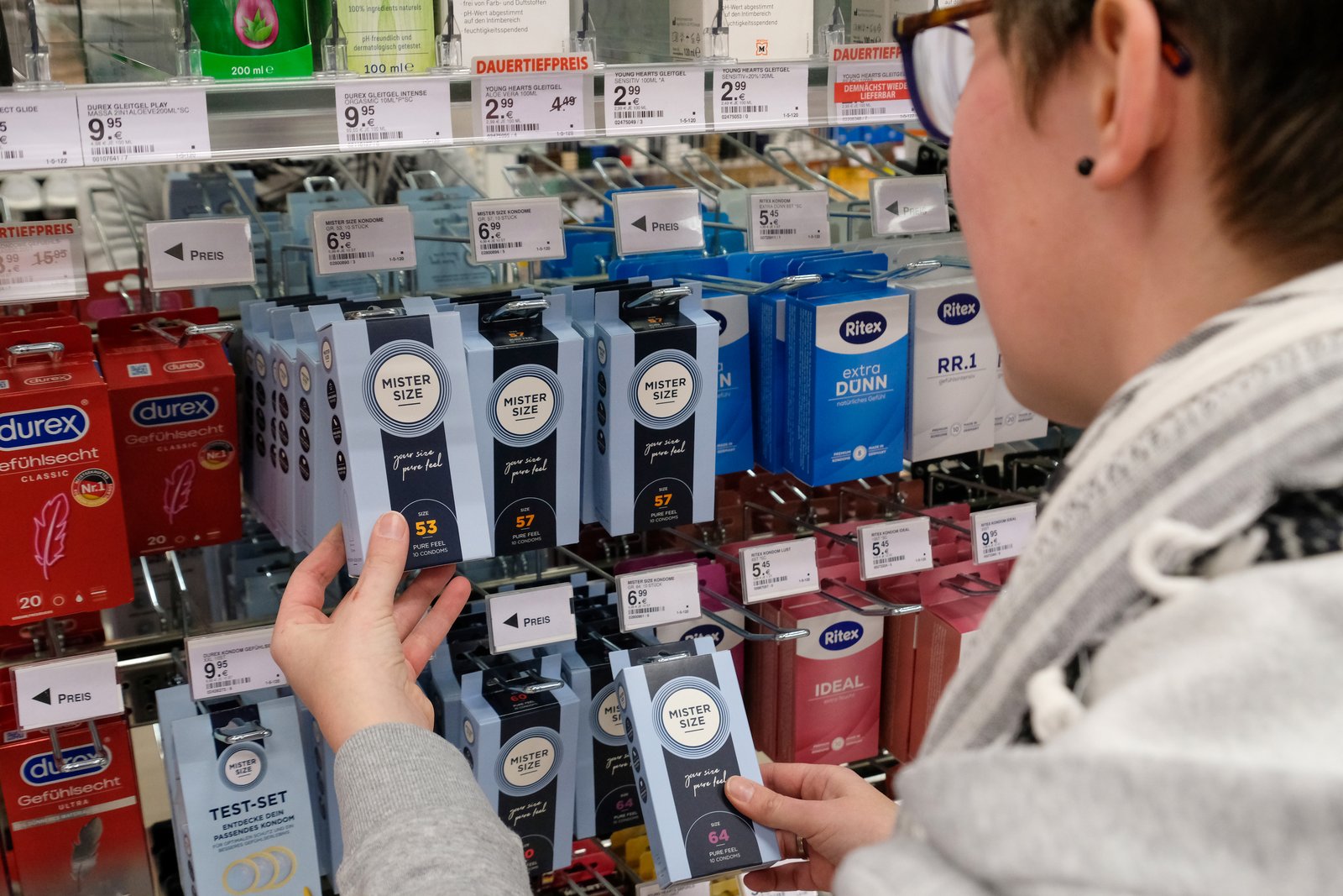 Eine Kundin vor dem Kondomregal mit Mister Size Kondomen im Müller Drogeriemarkt