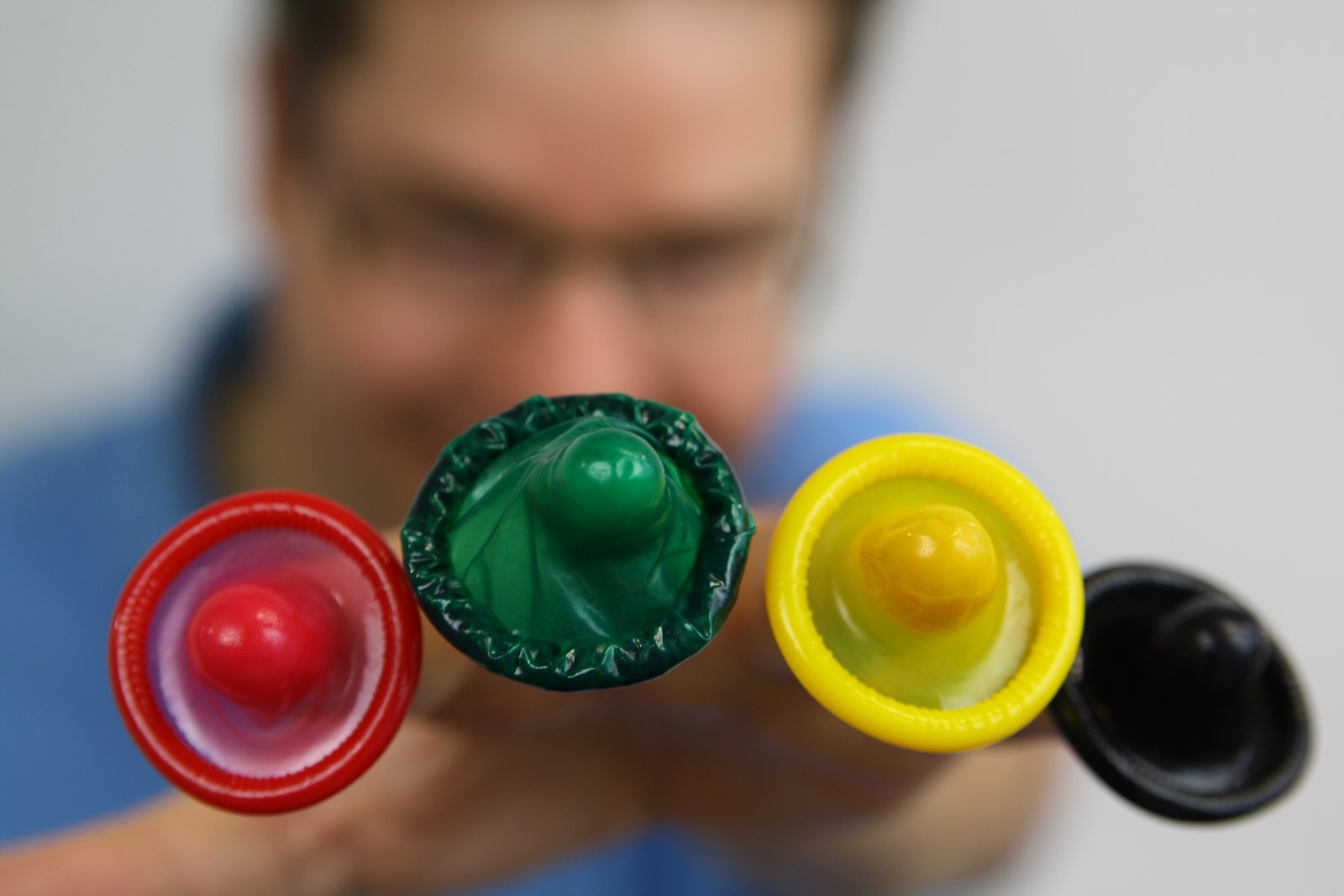 Jan Vinzenz Krause mit bunten Kondomen in rot, grün, gelb und schwarz